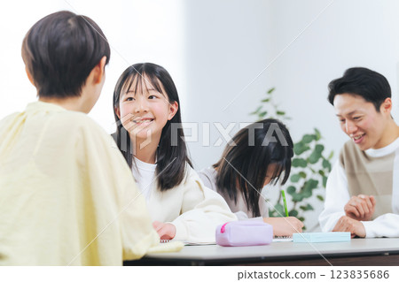 Two girls studying and a man and a woman teaching them Two girls studying and a man and a woman teaching them 123835686