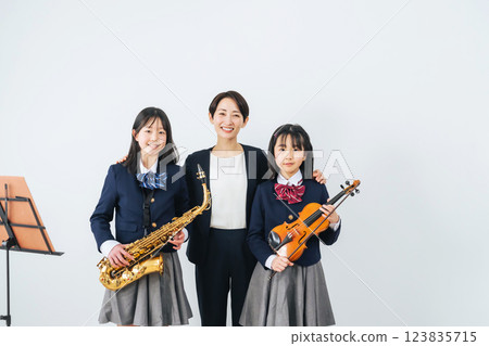 一群女學生和一位拿著薩克斯風和小提琴的女老師 一群女學生和一位拿著薩克斯風和小提琴的女老師 123835715