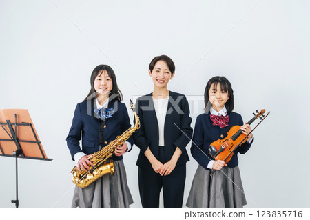 一群女學生和一位拿著薩克斯風和小提琴的女老師 123835716