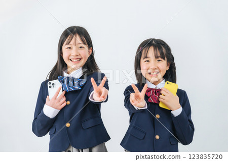 Group of female students making peace signs while holding smartphones 123835720