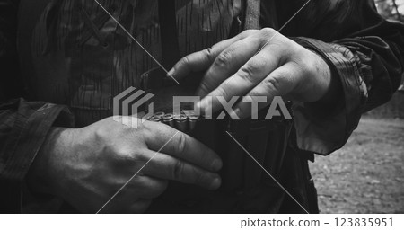 Reenactor Dressed As German Infantry Soldier Packing Chest Bandolier. Close-up View On Wermacht German Military Uniform During Ww2. Reenactment Tactic Game. Cartridge Belt Detail. Black And White Reenactor Dressed As German Infantry Soldier Packing Chest Bandolier. Close-up View On Wermacht German Military Uniform During Ww2. Reenactment Tactic Game. Cartridge Belt Detail. Black And White 123835951