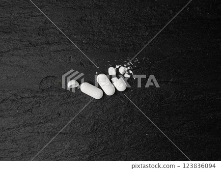 Broken Pills, Crushed Aspirin, Split Tablet, Broken Pill Capsules, Crumbling White Drugs on Black 123836094