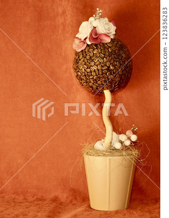Artificial flower in the form of a ball made of coffee nuts on a red background Artificial flower in the form of a ball made of coffee nuts on a red background 123836283