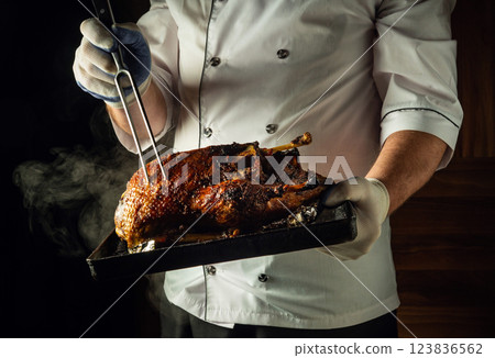 A skilled chef holds a tray with a perfectly roasted piece of duck meat, with steam swirling around it. The warm atmosphere of the kitchen enhances the cozy atmosphere of culinary mastery A skilled chef holds a tray with a perfectly roasted piece of duck meat, with steam swirling around it. The warm atmosphere of the kitchen enhances the cozy atmosphere of culinary mastery 123836562