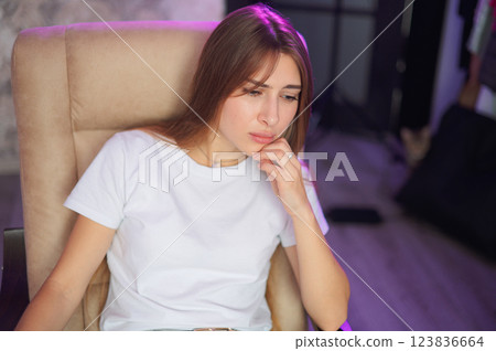 Young woman frustrated, sitting on sofa in modern living room during daytime sad emotions 123836664