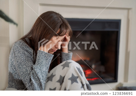 Young woman experiencing headache migraine while sitting on a couch in a modern living room home during daytime 123836691