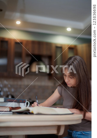 Female student learning and preparing exam at home. Woman reading textbook and taking notes Female student learning and preparing exam at home. Woman reading textbook and taking notes 123836698
