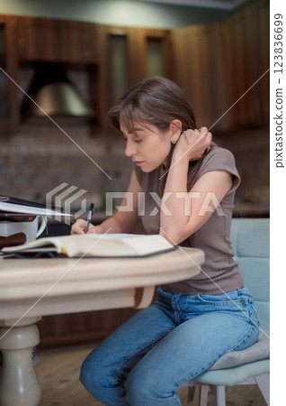 Female student learning and preparing exam at home. Woman reading textbook and taking notes Female student learning and preparing exam at home. Woman reading textbook and taking notes 123836699