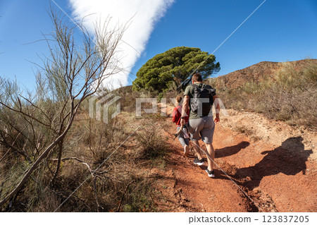Caucasian adults and child hiking on sunny trail in nature Caucasian adults and child hiking on sunny trail in nature 123837205