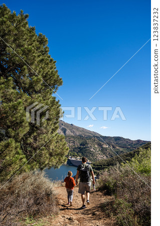 Father and son hiking on scenic mountain trail near lake, La Concepcion reservoir in Marbella Father and son hiking on scenic mountain trail near lake, La Concepcion reservoir in Marbella 123837232