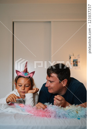 Caucasian father and young daughter in unicorn costume enjoy playtime together indoors Caucasian father and young daughter in unicorn costume enjoy playtime together indoors 123837257