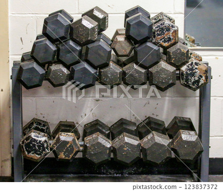 Heavy Dumbbells Lined up on a Rack in a Gym With Noticeable Wear and Tear 123837372