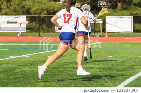 Female Lacrosse Players Compete on the Field During a Sunny Afternoon Female Lacrosse Players Compete on the Field During a Sunny Afternoon 123837397