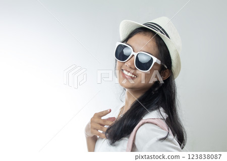 close up of young woman in white suit, wearing glasses, beach hat smiling broadly, isolated white background close up of young woman in white suit, wearing glasses, beach hat smiling broadly, isolated white background 123838087