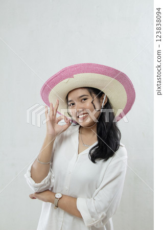 Beautiful and elegant young Asian woman wearing summer hat and okay hand gesture while smiling isolated on white background. advertising studio portrait of woman 123838094