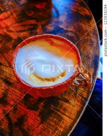 Cappuccino Moment: Frothy Delight in Rustic Clay Cup on Aged Wood Tabletop. High quality photo 123838194