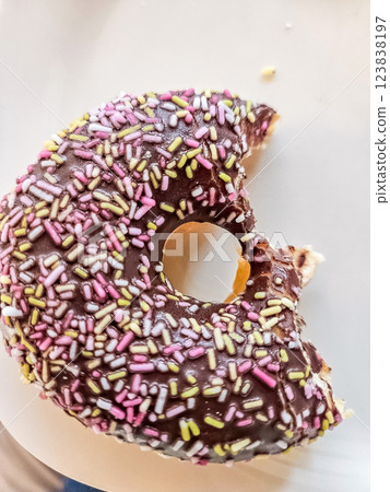 Partially eaten chocolate donut with colorful sprinkles on a white plate. High quality photo Partially eaten chocolate donut with colorful sprinkles on a white plate. High quality photo 123838197
