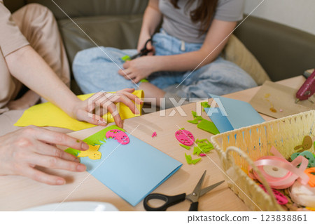 Mother and daughter creating Easter greeting cards with colorful felt cutouts. 123838861