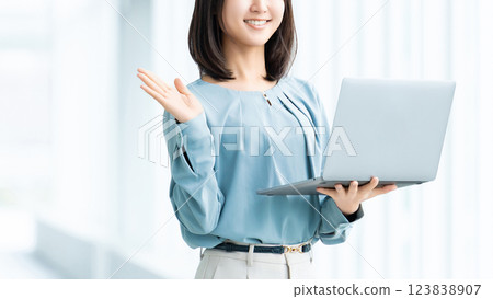 A smiling woman/businesswoman giving directions while holding a laptop 123838907