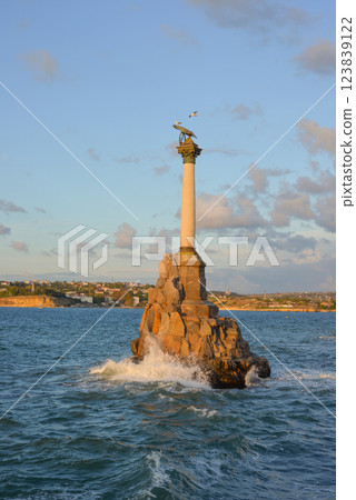 Monument to sunken ships on the city embankment against the backdrop of a stormy sea and rainy clouds at sunset. Sevastopol, Crimea. 123839122