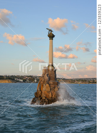 Monument to sunken ships on the city embankment against the backdrop of a stormy sea and rainy clouds at sunset. Sevastopol, Crimea. 123839123