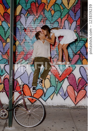 A couple poses by a colorful heart mural in the city, happily enjoying each other 123839239