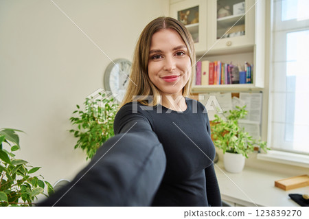 Close-up selfie portrait of young cheerful woman looking at web camera 123839270