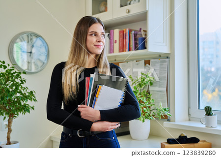 Portrait of woman university student holding textbooks notebooks, in home 123839280
