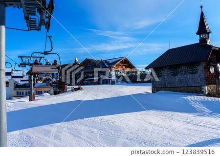 A ski resort with a chairlift, a building, and a clock tower in the background 123839516