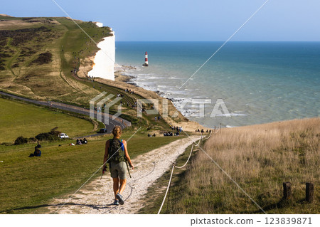 Beachy Head Lighthouse and Seven Sisters coastline with a hiker enjoying the scenic trail Beachy Head Lighthouse and Seven Sisters coastline with a hiker enjoying the scenic trail 123839871