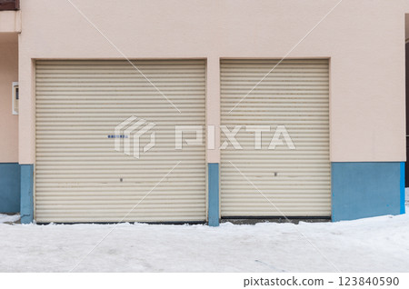 Two closed garage doors on a building with snow on the ground Two closed garage doors on a building with snow on the ground 123840590