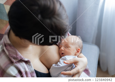Newborn baby peacefully sleeping after breastfeeding in warm mother embrace at home. No face mother breastfeeding and hugging baby. Lactation infant concept. Baby eating milk before he sleeping. Newborn baby peacefully sleeping after breastfeeding in warm mother embrace at home. No face mother breastfeeding and hugging baby. Lactation infant concept. Baby eating milk before he sleeping. 123840942