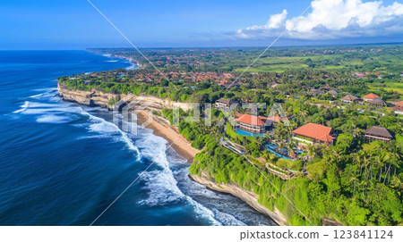 Aerial view of resort buildings nestled on a lush green cliff overlooking the ocean in bali 123841124