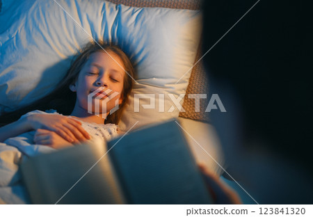 mother reading a book to her daughter mother reading a book to her daughter 123841320