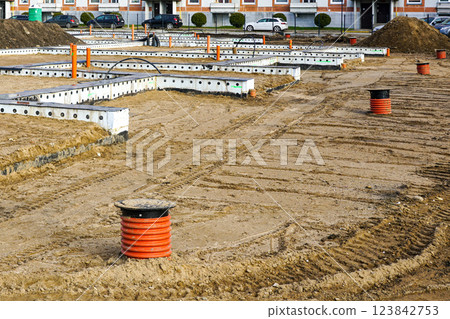 Row house construction site with prepared concrete foundations and underground utilities Row house construction site with prepared concrete foundations and underground utilities 123842753