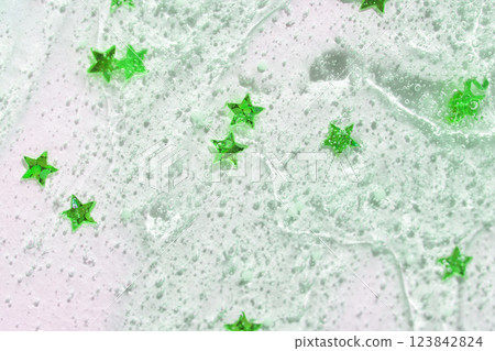 Green star confetti on translucent gel surface with bubbles in abstract textured 123842824