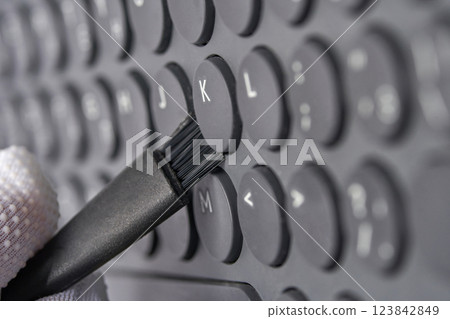 Close up of gloved hand cleaning keyboard with small brush for maintenance Close up of gloved hand cleaning keyboard with small brush for maintenance 123842849