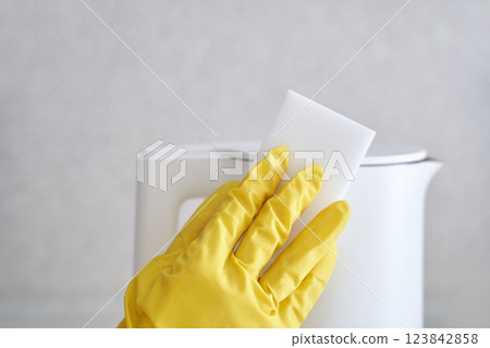 Cleaning white electric kettle with yellow glove using white sponge Cleaning white electric kettle with yellow glove using white sponge 123842858