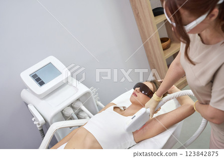 Young caucasian female receiving laser hair removal treatment in modern 123842875