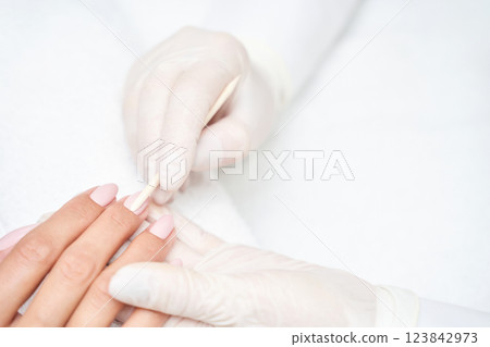 Close up of professional manicure procedure with gloved hands applying cuticle 123842973