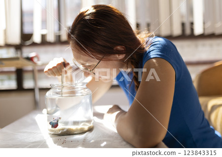 Woman cleaning fishbowl with small net in sunlight 123843315