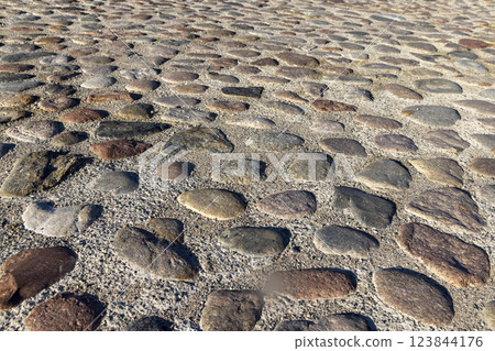 a part of the road made of cobblestones, an old-style pavement 123844176
