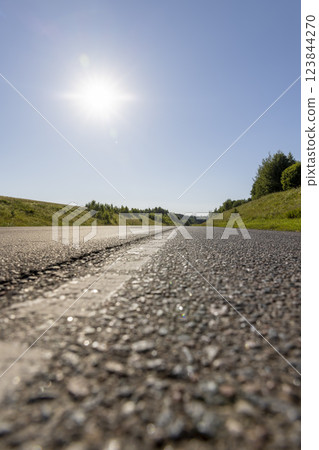 an empty straight paved road against a blue sky background 123844270