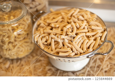 Different types of pasta. Many sorts of raw pasta in a cafe, food banner. Uncooked pasta in glass jar and colander, closeup 123844669
