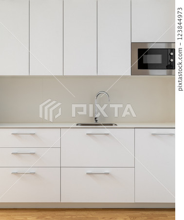 Modern kitchen with minimalist design, white cabinets, and wooden flooring for elegance 123844973
