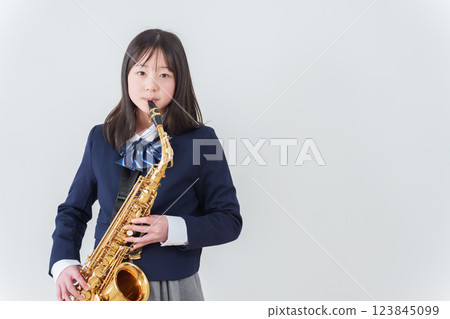 A female student in a brass band playing the saxophone 123845099