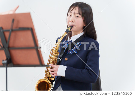A female student in a brass band playing the saxophone 123845100