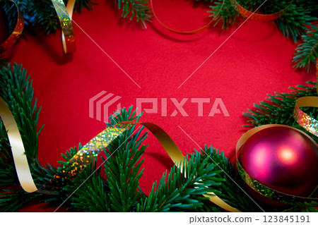 Red bright Christmas background. Winter frame of green branch, cones, gold tape for decor on the textured fabric background. Copy space. Top view. Red bright Christmas background. Winter frame of green branch, cones, gold tape for decor on the textured fabric background. Copy space. Top view. 123845191