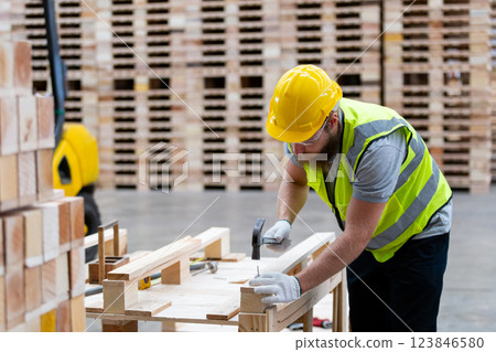 Worker constructs wooden furniture in a warehouse during daylight hours 123846580