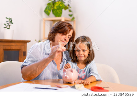 Grandmother and granddaughter inserting coins in Grandmother and granddaughter inserting coins in 123846589